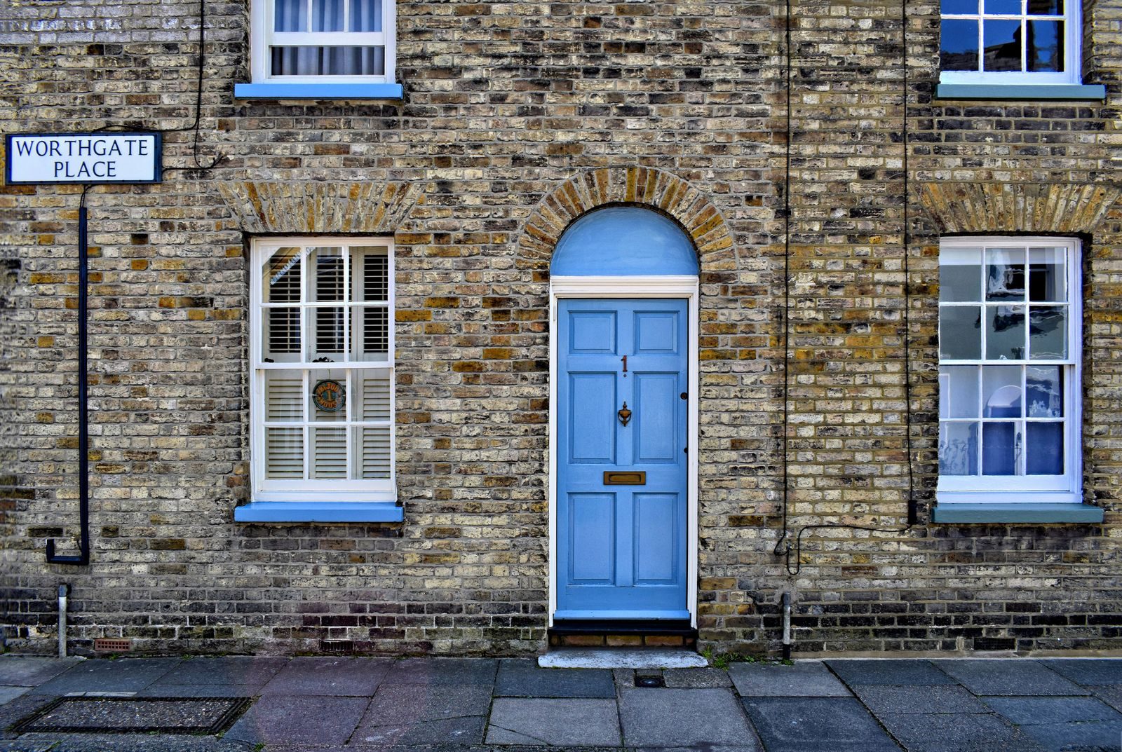 A blue composite-style front door on a traditional brick terrace house